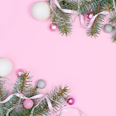 Fotokopi alanı ve pembe ve beyaz süslemelerle süslenmiş gümüş çam dallarıyla pembe arkaplan. Düz yatıyordu