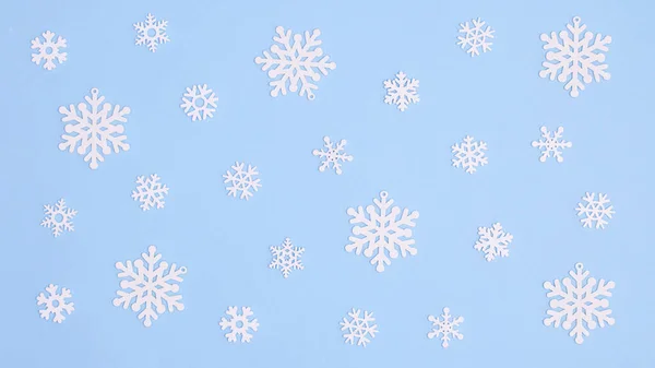 Pastel mavi arka planda kar taneleri deseni var. Düz bir Noel ve kış konsepti