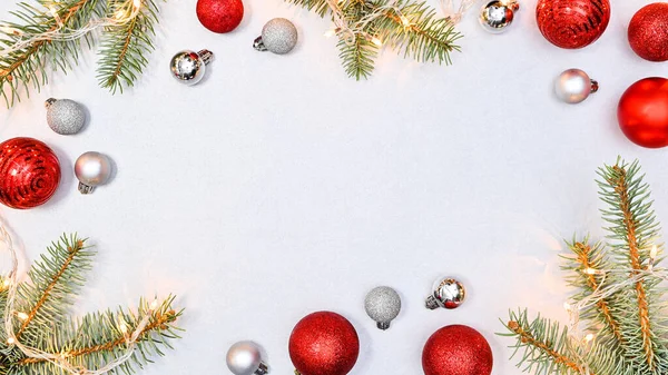 Kırmızı ve gümüş Noel topları ve beyaz arka planda ışık ve fotokopi alanı olan köknar dalları. Düz yatıyordu