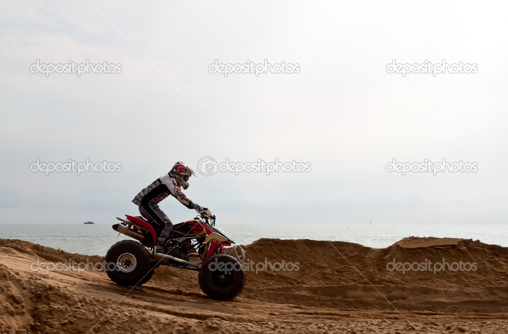 Sportsman driving a quadricycle on the sandy beach