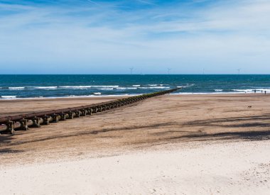 Cambois beach with old sewage pipeline and wind turbines.