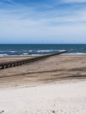 Cambois beach with old sewage pipeline and wind turbines.