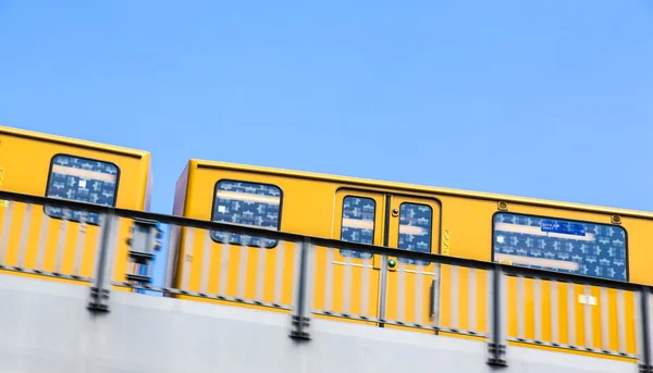 黄柏林地铁在孤立在蓝蓝的天空上的一座桥上移动 — 图库照片