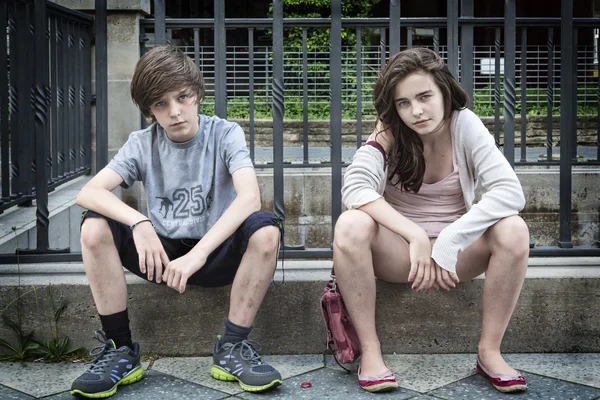 Dos sucios adolescentes urbanos sentados en una pared Imagen de archivo