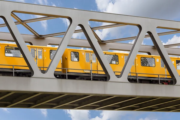 Yellow moving train on an iron bridge with blue sky — Stock Photo, Image