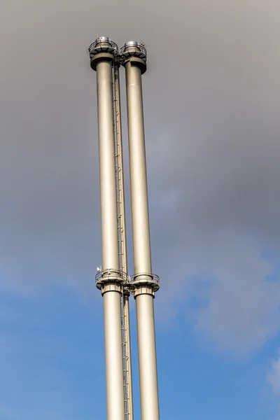 Twee metalen schoorstenen tegen de blauwe hemel met donkere wolken — Stockfoto