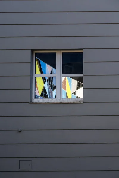 Venster op een zwart huis muur met gekleurde gespiegelde — Stockfoto