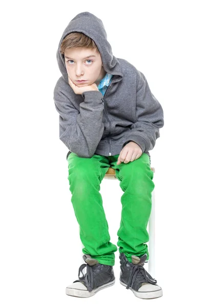 Serious teenager boy is sitting on a stool, isolated on white — Stock Photo, Image