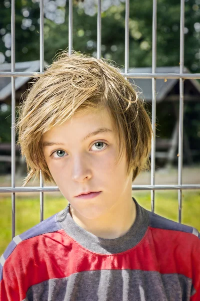 Porträtt av en manlig tonåring framför ett metall rutnät — Stockfoto