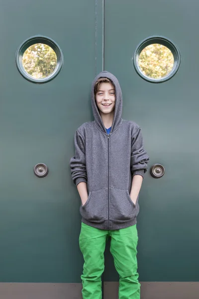 Portret van een glimlachende mannelijke tiener voor een groene metalen doen — Stockfoto