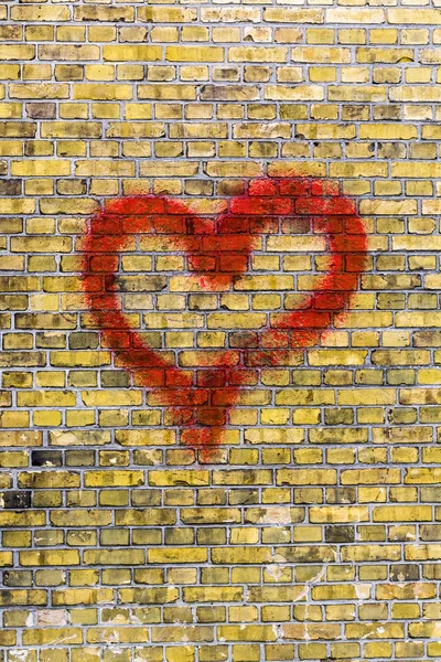 Hjärtat graffiti på en gul tegel vägg bakgrund — Stockfoto
