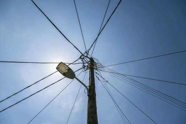 Old street light with many cables connected, isolated on blue sk — Stock Photo, Image
