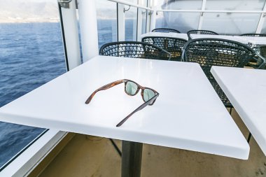 okyanusun içinde geçmiş olan beyaz bir tablo üzerinde döşeme güneş gözlüğü