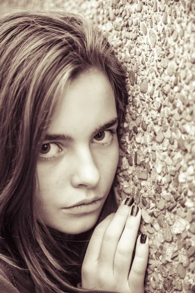 Portrait of a female teenager leaning here face on a wall, with — Stock Photo, Image