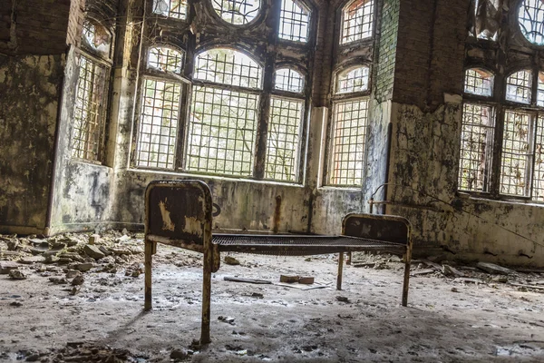 Old rusty bed in ruinous house in front of some windows — Stock Photo, Image