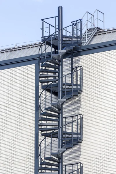 Dark blue circular staircase on a white brick wall — Stock Photo, Image