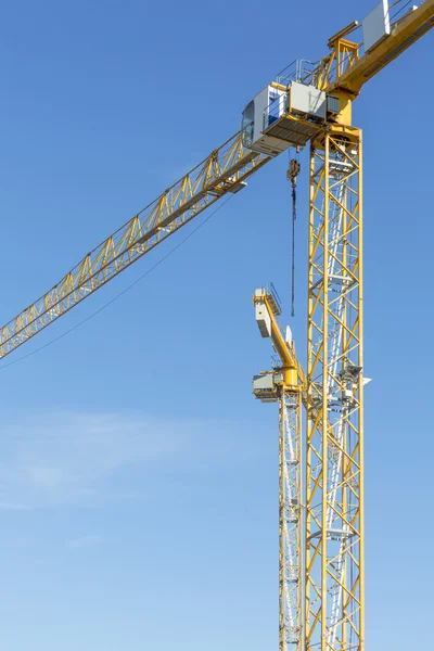 Zwei gelbe Baukräne isoliert am blauen Himmel — Stockfoto