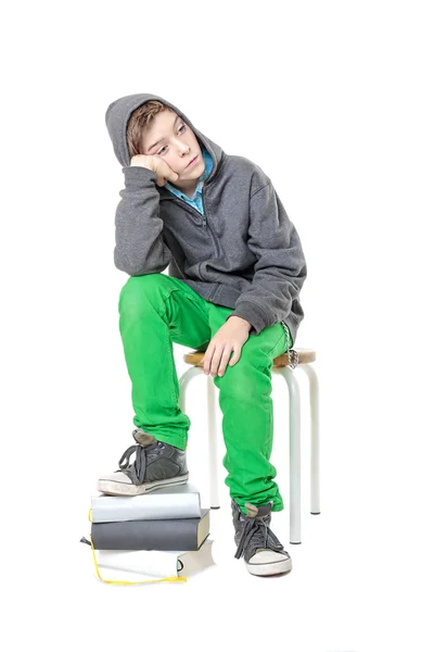 Sad male sitting  teenager with one foot on a stack of books, is — Stock Photo, Image