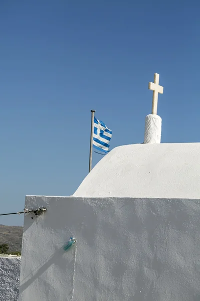 Грецький прапор за білою каплицею, ізольований на блакитному небі — стокове фото