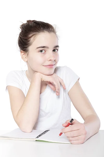 Glimlachend vrouwelijke tiener met lege nota boek zitten aan een tafel, — Stockfoto