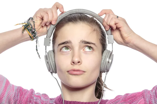 Beautiful teenager girl fumble on her headphones, isolated on wh — Stock Photo, Image