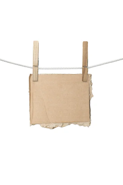 Rasgado pedaço de placa de cartão pendurado em duas espinhas de roupa, isolado — Fotografia de Stock