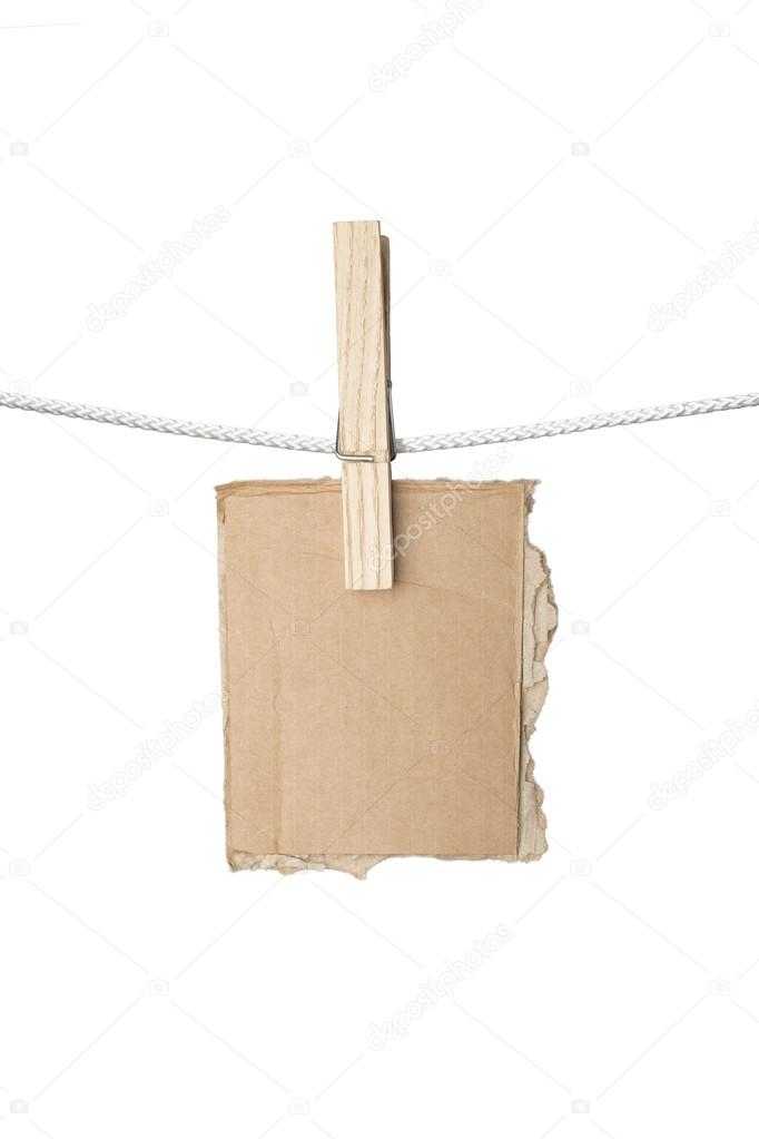 ripped piece of card board hanging on one clothespin, isolated o