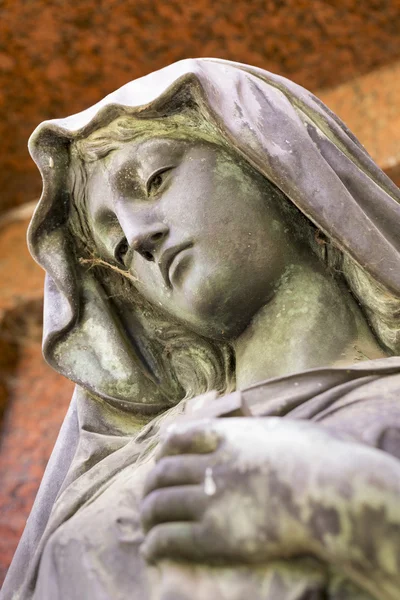赤い背景のマリアのブロンズ彫刻 — ストック写真