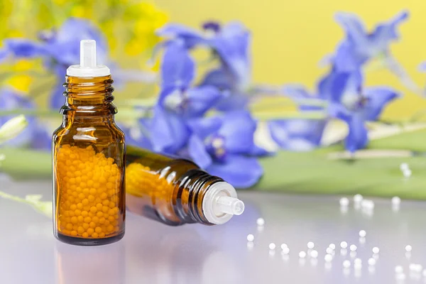 Two bottles with homeopathy globules and flowers, with purple re — Stock Photo, Image