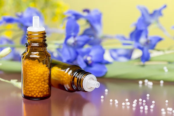 Two bottles with homeopathy globules and flowers, with red refle — Stock Photo, Image