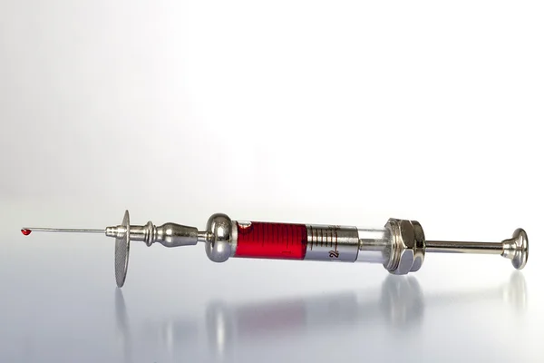 Vintage syringe with blood on reflecting underground — Stock Photo, Image