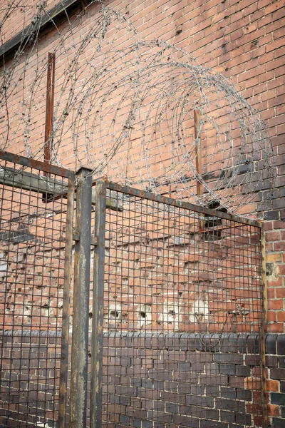 Barb wire op een oude hek met rode bakstenen muur — Stockfoto
