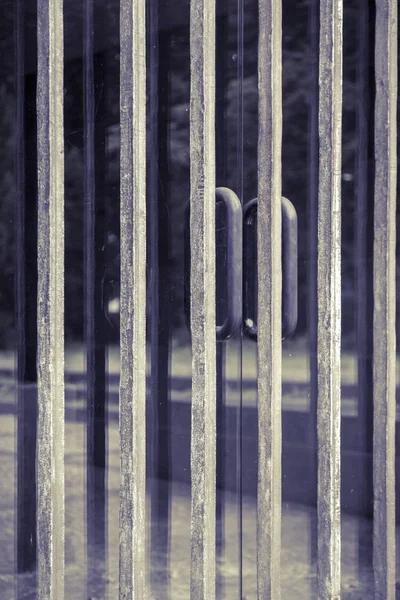 Металлическая решетка перед стеклянной дверью — стоковое фото