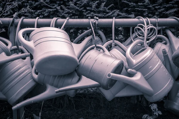 Some old watering cans on a rusty pipe — Stock Photo, Image