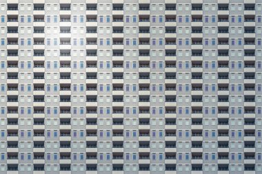 Mimari desen, kasvetli gri beton cepheli ve balkonlu yüksek katlı bina.