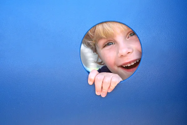 Bambino peeking attraverso foro a parco giochi — Foto Stock