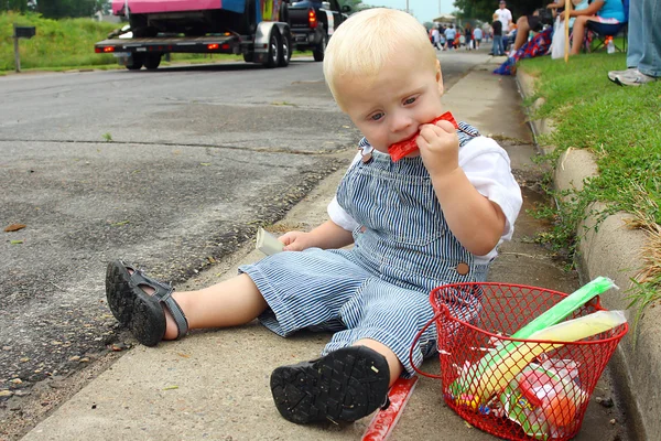 Dítě sedí na přehlídce jíst cukroví — Stock fotografie