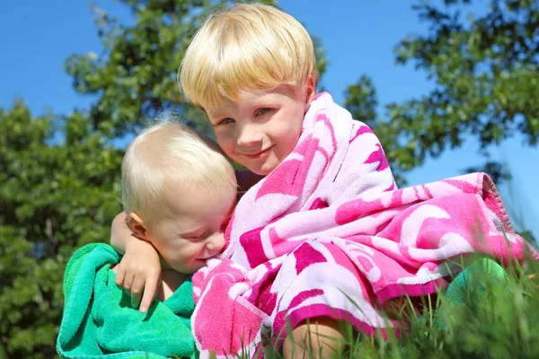 Hermano mayor y bebé abrazándose en toallas de playa —  Fotos de Stock