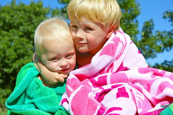 Irmãos bonitos abraçando em toalhas de praia — Fotografia de Stock