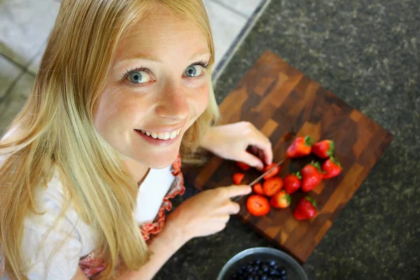 Mujer rebanando fresas frescas en su cocina —  Fotos de Stock