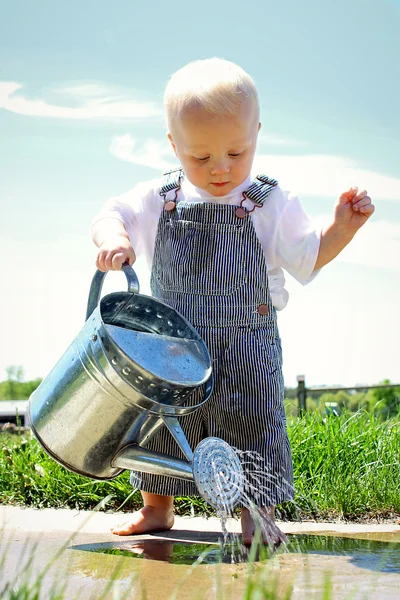 Baby vattning trottoaren med tenn vatten kan — Stockfoto