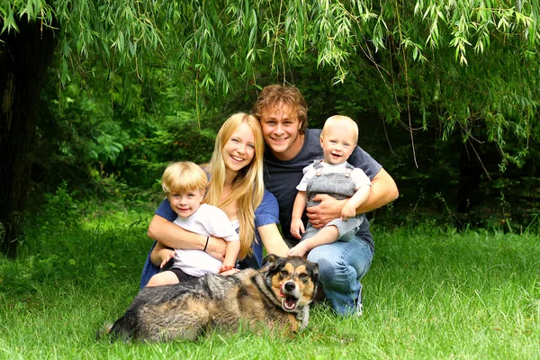 버드 나무 아래에 앉아 행복 한 가족 — 스톡 사진