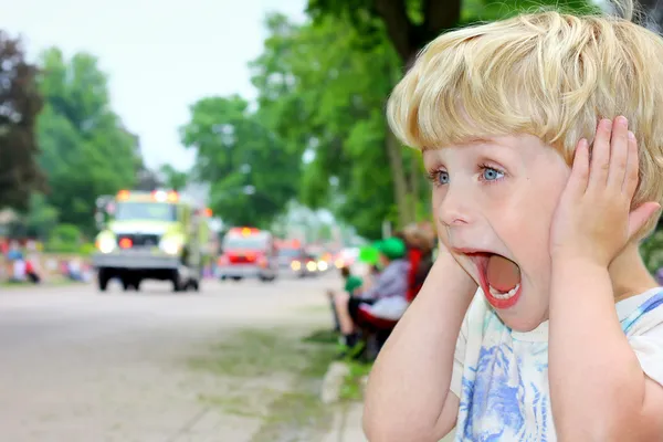 Dítě pokrývající uši na hlasité parade — Stock fotografie