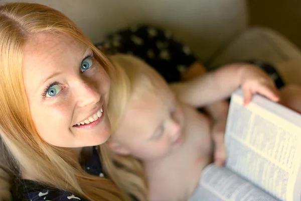 Женщина читает книгу, держа ребенка на руках — стоковое фото