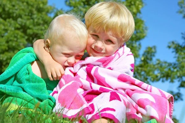 Irmãos abraçando em toalhas de praia — Fotografia de Stock