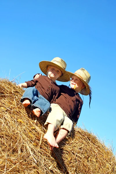 Щасливий великий брат і дитина сидить на Hay Bale зовні — стокове фото