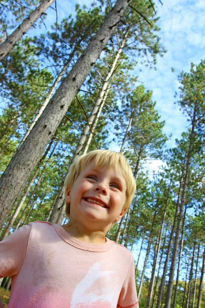 Šťastný chlapec stojící mimo pod les borovice — Stock fotografie