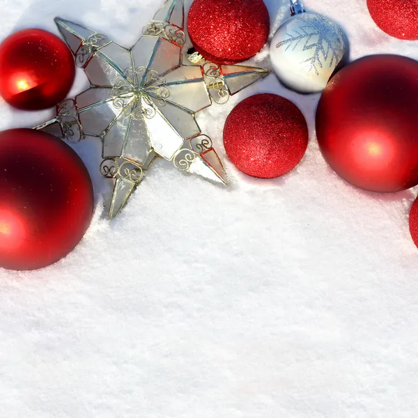 Bolbos de Natal vermelho e estrela na fronteira branca da neve — Fotografia de Stock