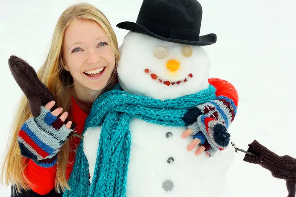 Mujer feliz abrazando a muñeco de nieve afuera en invierno —  Fotos de Stock