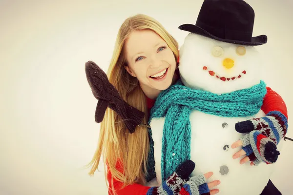 Vrouw en sneeuwpop buiten in de winter — Stockfoto